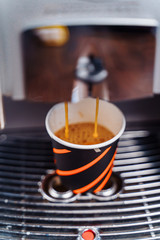 Fototapeta premium The budget model of the coffee machine prepares a delicious, fragrant espresso. Freshly brewed coffee is poured from the coffee machine into cup in the kitchen at home