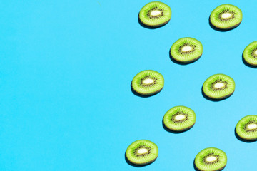 Summer abstract trendy fresh concept. Kiwi pattern on bright light blue background, copy space. Minimal flat lay food texture.