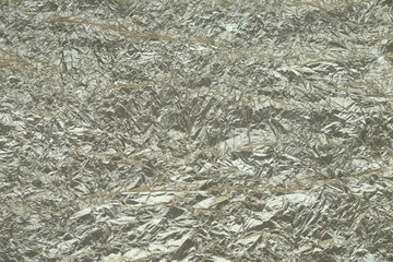Abstract textured wrinkled tin foil background.Crumpled foil paper texture for background.Surface of crumpled  foil with a hint of silver and gold for backdrop.