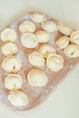 Fototapeta na wymiar freshly molded homemade dumplings lie on a wooden board. A photo of the cooking process.