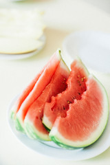 Cut slices of ripe appetizing watermelon lies in a plate on the table. A photo with a blurred background.