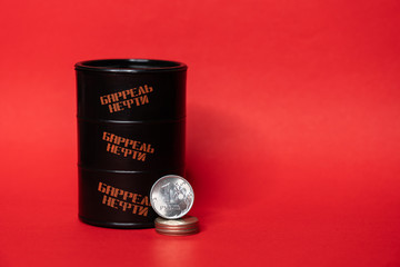 Black oil barrel with a one ruble coin on a red background