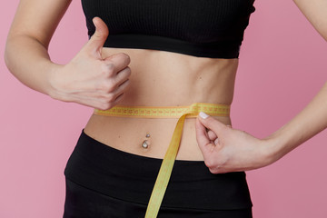 Fitness, workout, healthy lifestyle and diet concept - thin athletes women measure waist after...