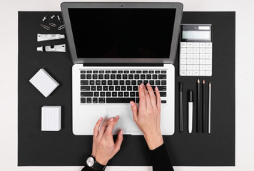 A man works with laptop, calculator, pens, pencils, card, phone on his desktop isolated on balck background
