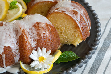 Lemon Ricotta Bundt Cake with icing displayed on a black decorative plate in a light bright airy setting.