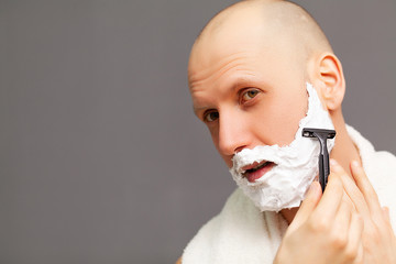 Man in the bathroom shaves his beard with a razor