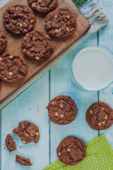 Chocolate cookies with a glass of milk on the light green wooden table in top view