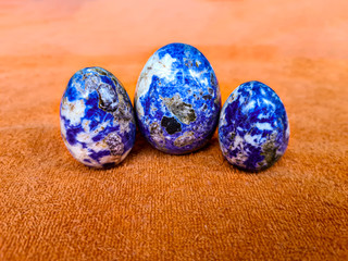 Three sodalite precious rock in an orange background.
