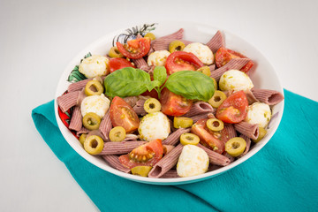 Pasta salad with mozzarella and cherry tomatoes, basil