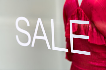 Shopping mall department clothing fashion store shop storefront sign closeup of sale on glass window closeup exterior with mannequin and clothes