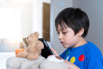 Kid self isolation using tablet for his homework,Child doing using digital tablet searching information on internet during covid-19 lock down,Social Distancing ,E-learning and online education