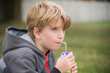 Portrait of a kid drinking juice with a straw