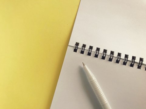 notebook and pen on yellow background