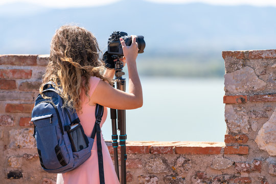 Castiglione del Lago, Italy in Umbria Rocca with Medievale o Rocca del Leone fort and young girl woman taking picture of lake Trasimeno with professional camera