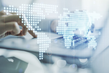 Double exposure of abstract digital world map and hand typing on laptop on background, big data and blockchain concept