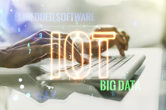 Double exposure of creative IOT hologram with hands typing on laptop on background, research and development concept