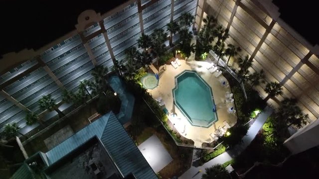 Top Down Aerial View Of Hotel Resort Plaza At Night With Pam Trees And Swimming Pool 