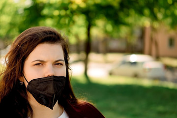 Angry young girl with flower in a black mask with flowers on the street. Quarantine walk.