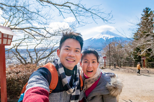 A couple takes a photo with mountain Fuji as background