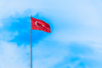 A huge Turkish flag waving in blue sky.