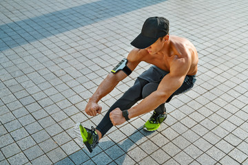 Sporty man doing squat on one leg. Photo of young man workout along outdoor in the city - obrazy, fototapety, plakaty