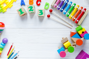Kids toys: pyramid, wooden blocks, xylophone, train on white wooden background. Top view. Flat lay. Copy space for text
