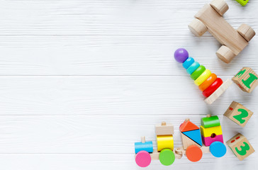 Kids toys: pyramid, wooden blocks, xylophone, train on white wooden background. Top view. Flat lay. Copy space for text
