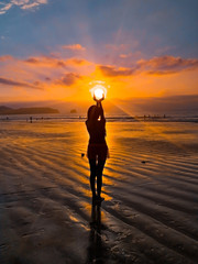 Woman walking on the beach at sunrise