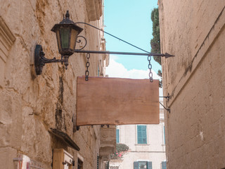 Wooden hanging rectangle sign on the background of vintage homes. old city, light colors,blue sky