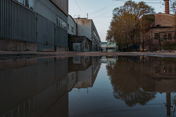 Industrial buildings reflected in pool of rainwater