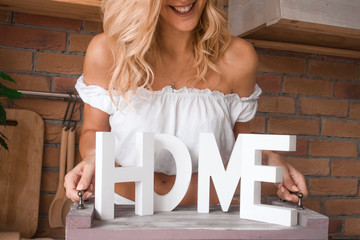 a beautiful young girl welcoming home guests carrying a tray with house decoration letters Home