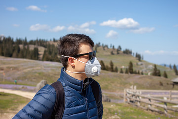 young man in mask and sunglasses walking outside