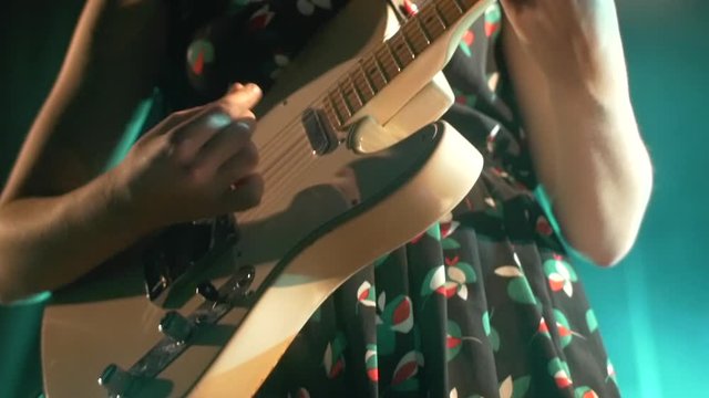 Female guitarist playing on stage at music festival