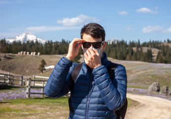 young man in mask and sunglasses walking outside