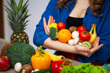 Concept of healthy eating and diet girl holding vegetables on background white wall.