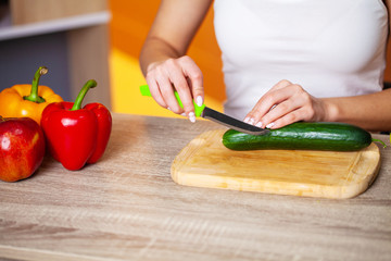Closeup of woman slices cucumber for fresh salad