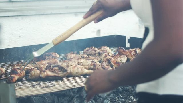 Woman turns chicken over on a barbecue
