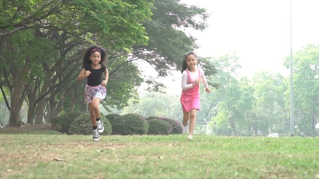 group two of kids running in the spring field at public park slowmotion. people children plying outdoors concept.