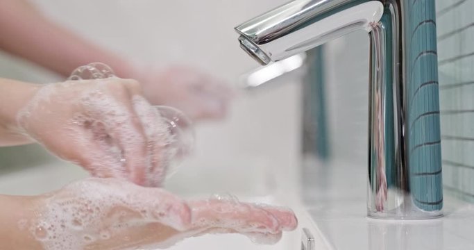 People is washing  his hands with a hand wash gel in sink. Coronavirus pandemic prevention wash hands with soap warm with water.  Children rubbing fingers washing frequently using hand sanitizer gel. 