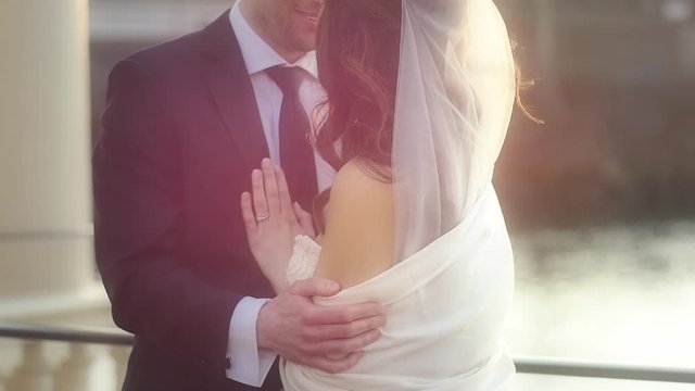 A newly married couple embrace at sunset after their wedding on the water