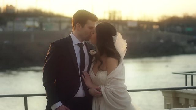 Newlyweds kiss at sunset on the river in slow motion