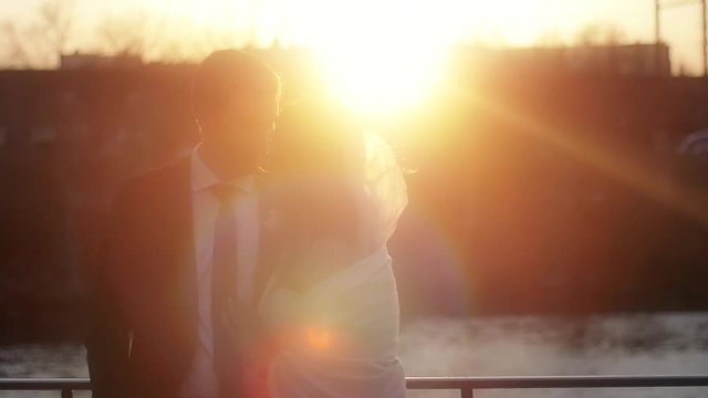 A silhouette of newlyweds then rising to the lens flare of the sunset behind them