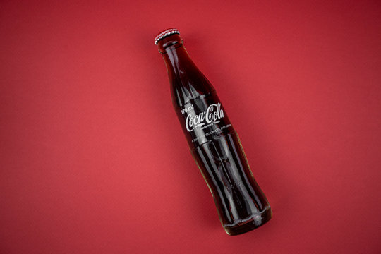 Atlanta, Georgia, USA &ndash; April 1, 2020: closeup of classic contour glass bottle of Coca Cola from USA lying on a red table. concept of globalism, global brand, worldwide spread.