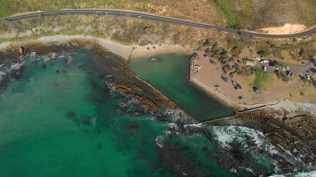Aerial drone view panning over rock pool on rocky shoreline of clarens drive Gordons bay