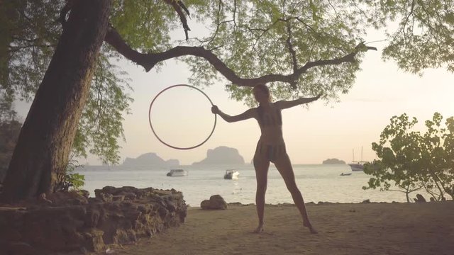 beautiful women dancing on beach Thailand vacation holiday with hula hoop next to a green tree, musical lady good redeem with circle, stripe bikini 4k amazing dance