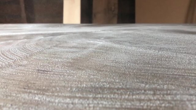 White powder being swept on and off of a wooden table. Unknown white substance being cut and sweeping on and off screen