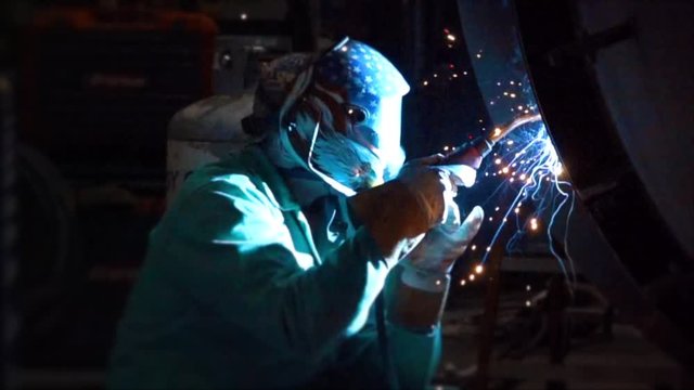 Panning slow motion shot of a welder with sparks flying towards him. 500fps