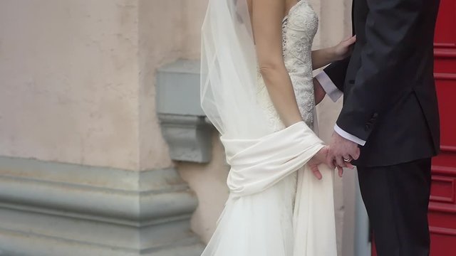 A bride and groom giggling and doing eskimo kisses in front of red church doors