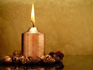 Christmas candle with decorations and elegant background in gold and brown colors. Lots of copy...