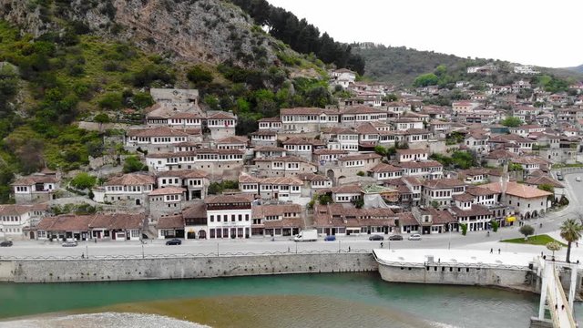 Medieval houses of Berat city with Otoman architecture style of white stone walls and thousand windows over turquoise water of Osumi river in Albania